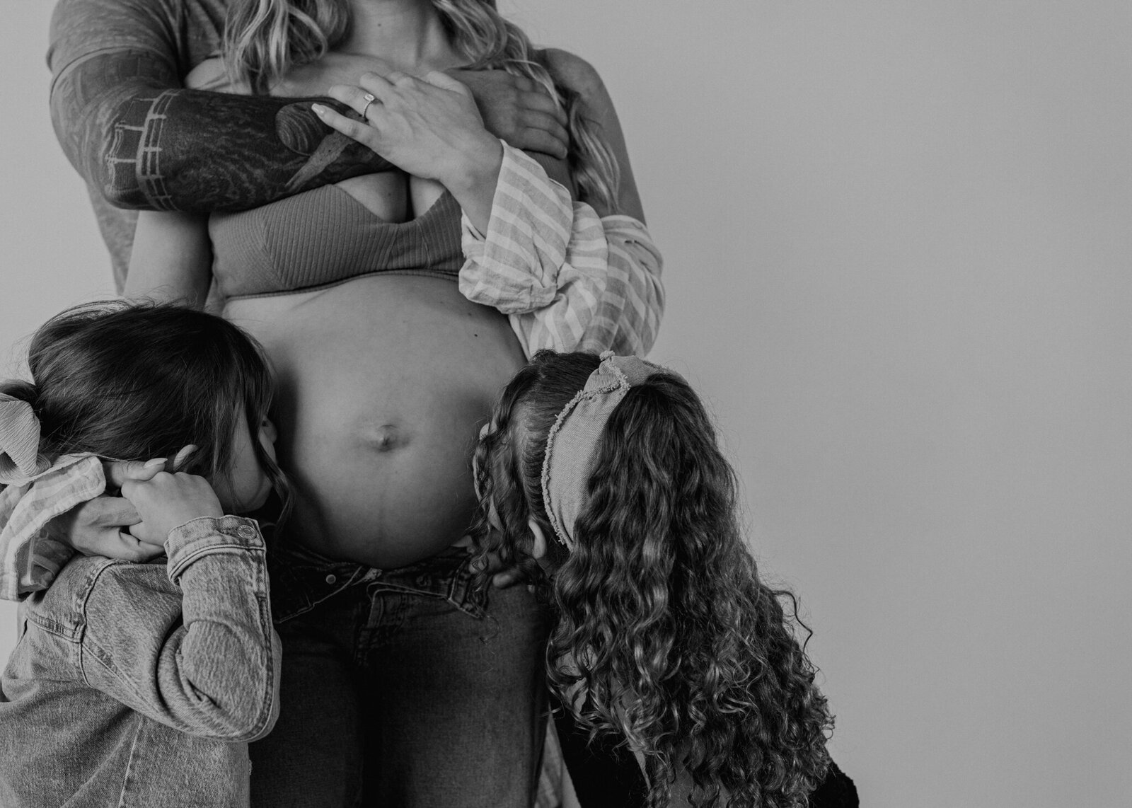 Big sisters kiss moms pregnant belly