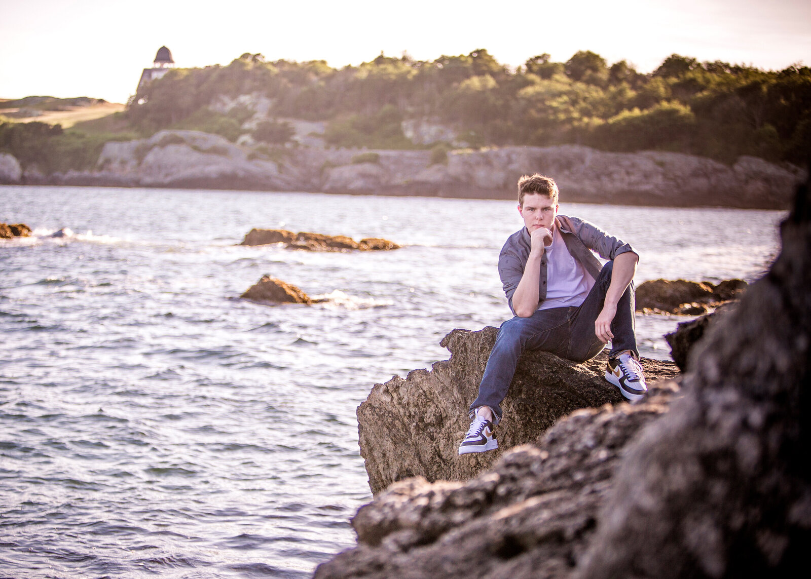  High school senior boy sitting on a rock over looking the ocean in Jamestown RI while posing for a Rhode Island Photographer