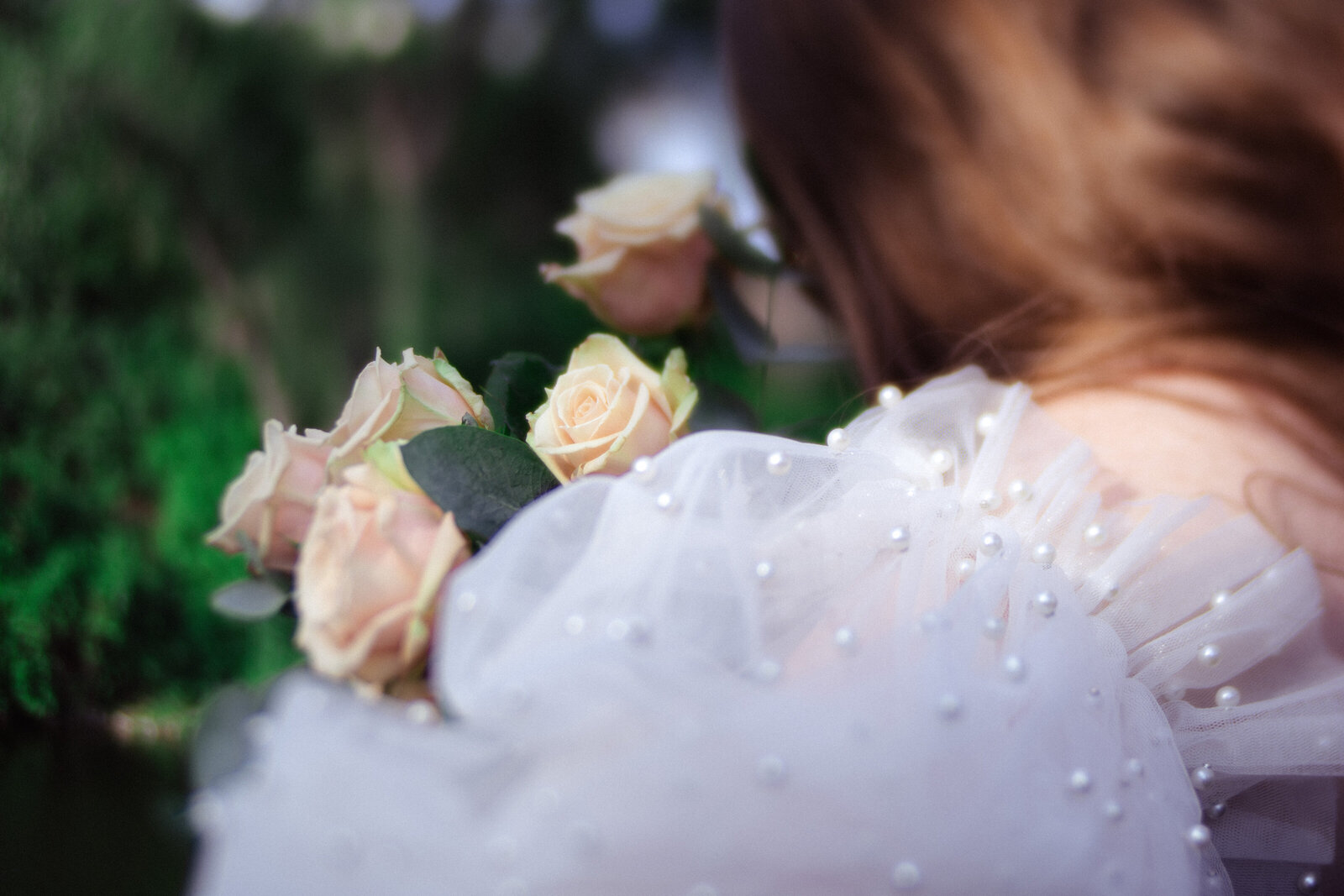 bride with pearl sleeves holds bespoke white rose boquet