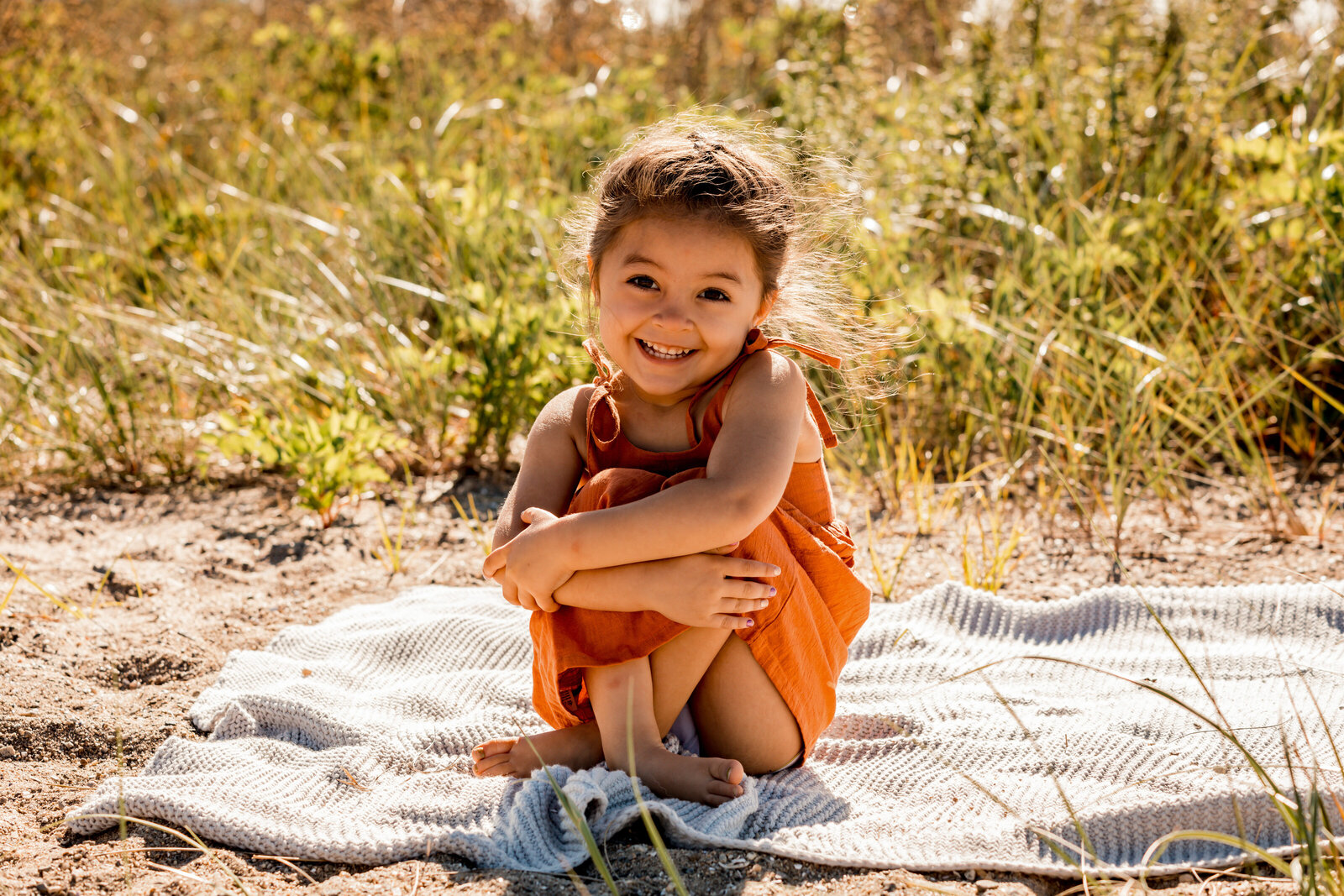 little gir sitting on the blanket at the bridgeport beach