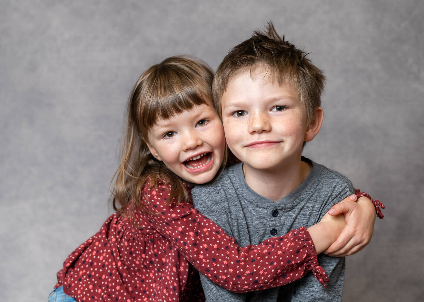Two kids hug one another, smiling.