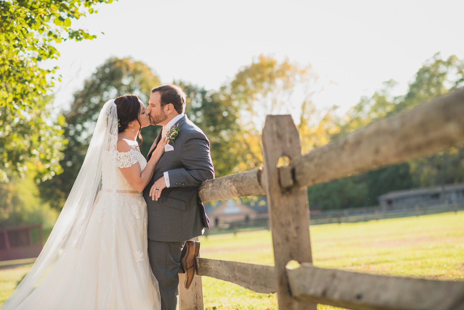 bride and groom kissing against barn at The Barn at Old Bethpage