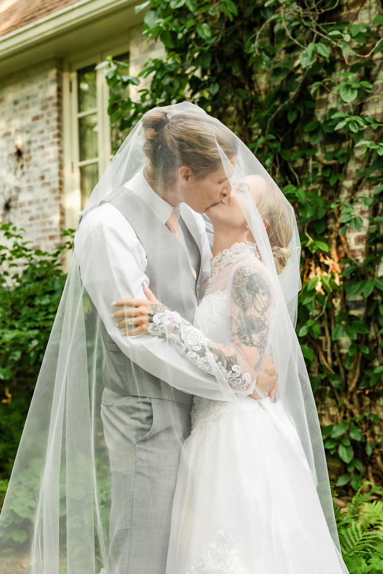 Bride and groom kissing underneath the bride's cathedral length veil during their newlywed portraits at their Nashville, TN backyard wedding