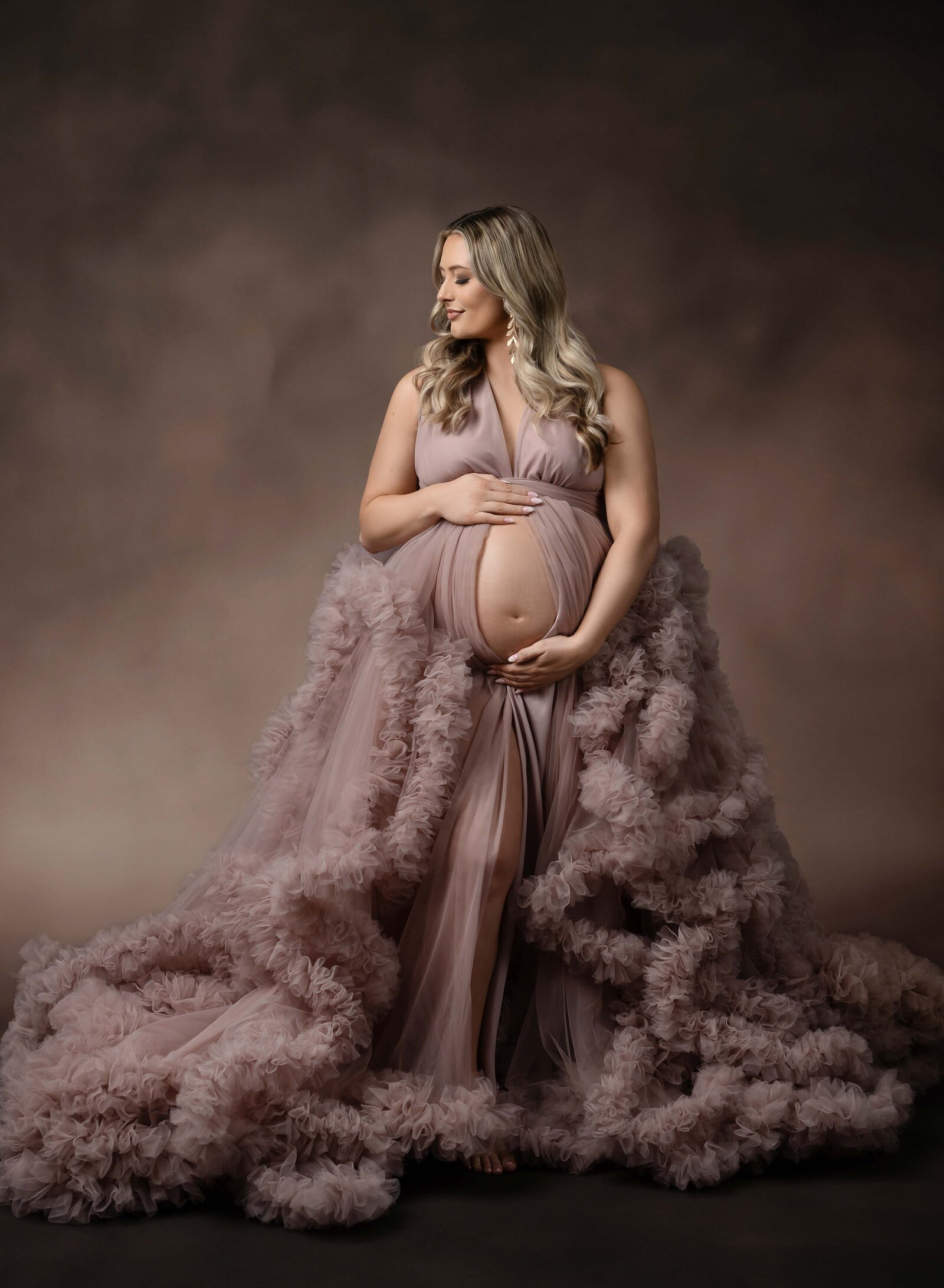 Mom holding baby bump and looking over her shoulder. Maternity portrait taken by Jenni. Nikki Photography at Atlanta Photo Studio. 