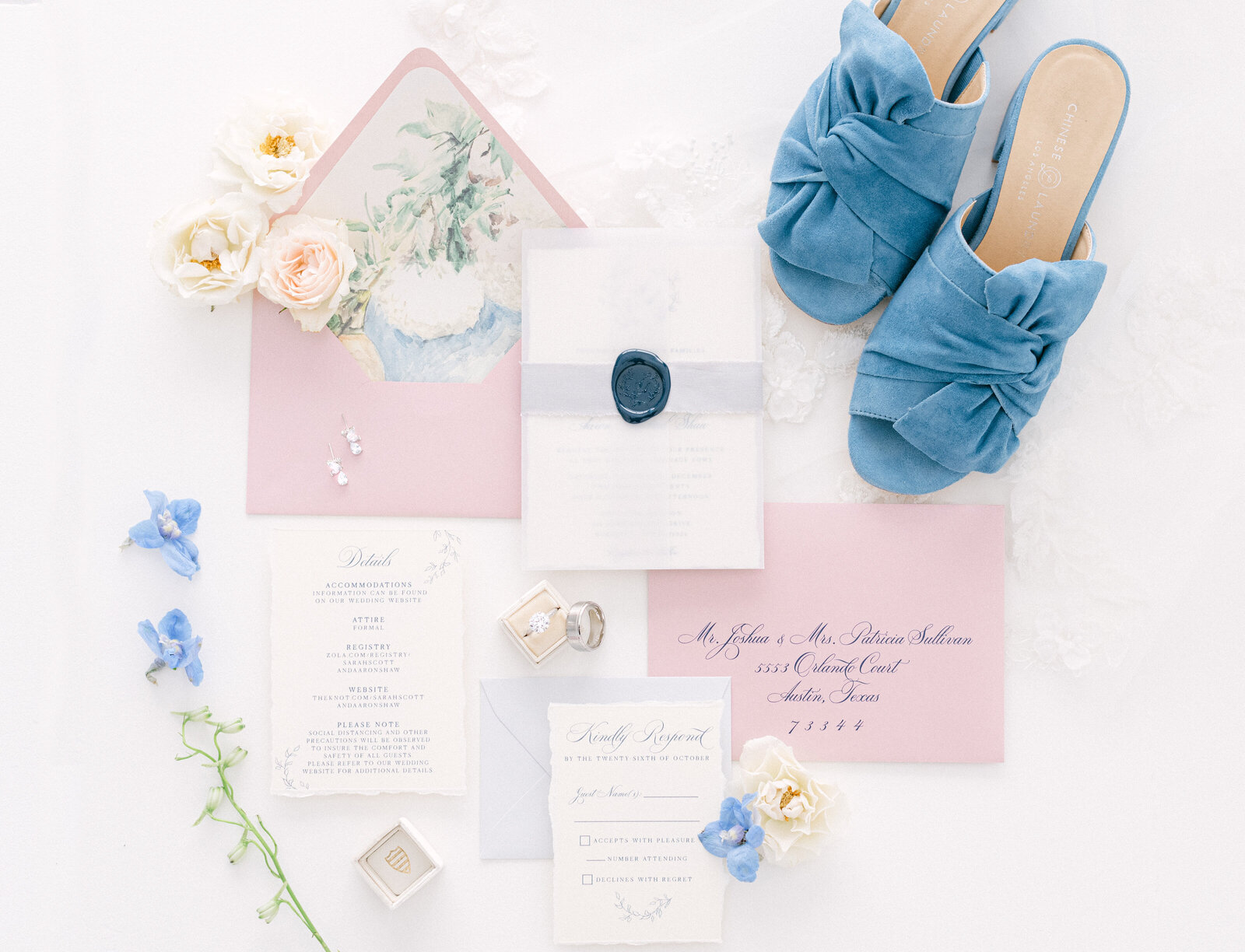 Portrait of various pink, white and blue wedding stationery with gray cursive font, blue heels, a wedding ring, and flowers