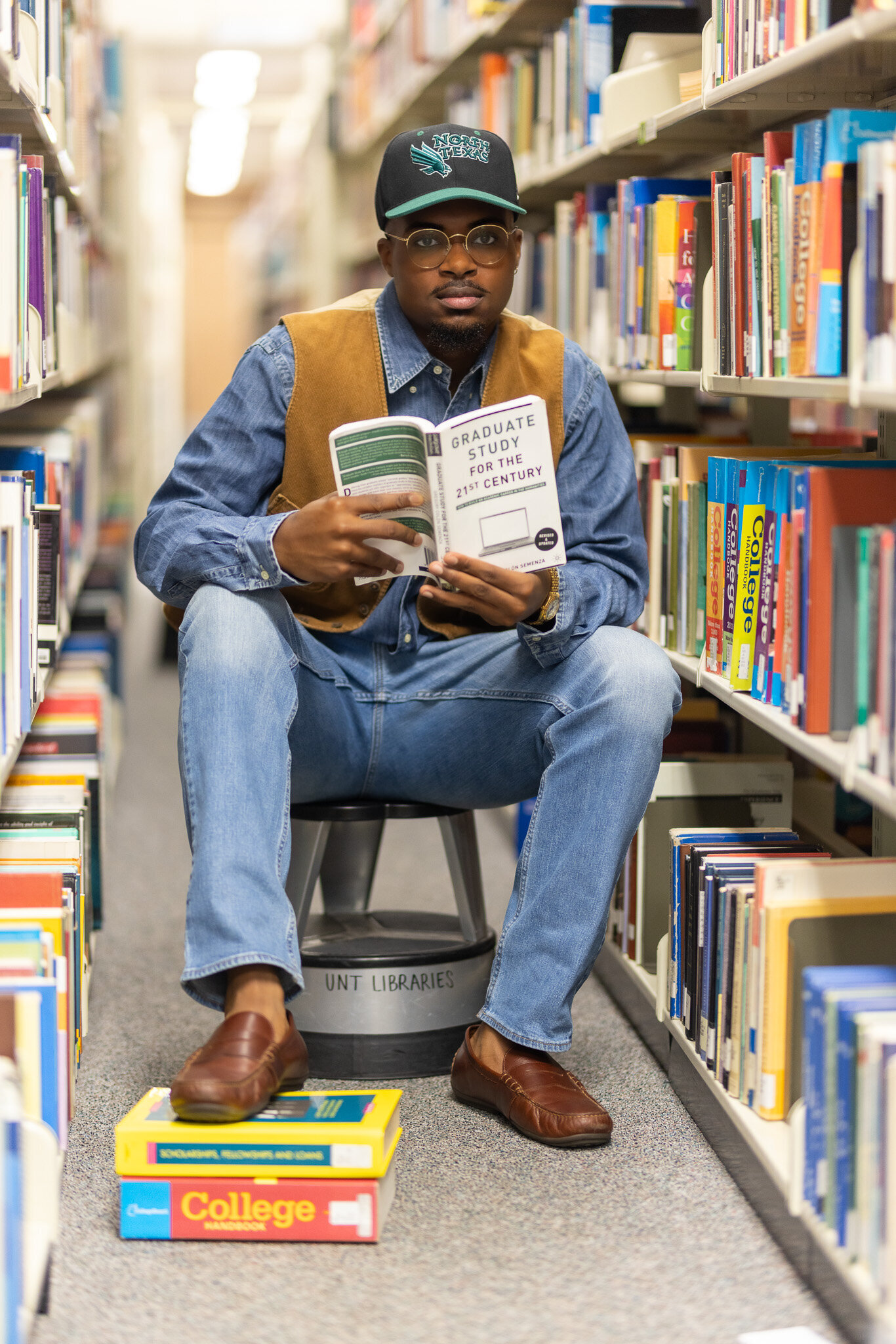 a man sitting among the bookshelves at a college library