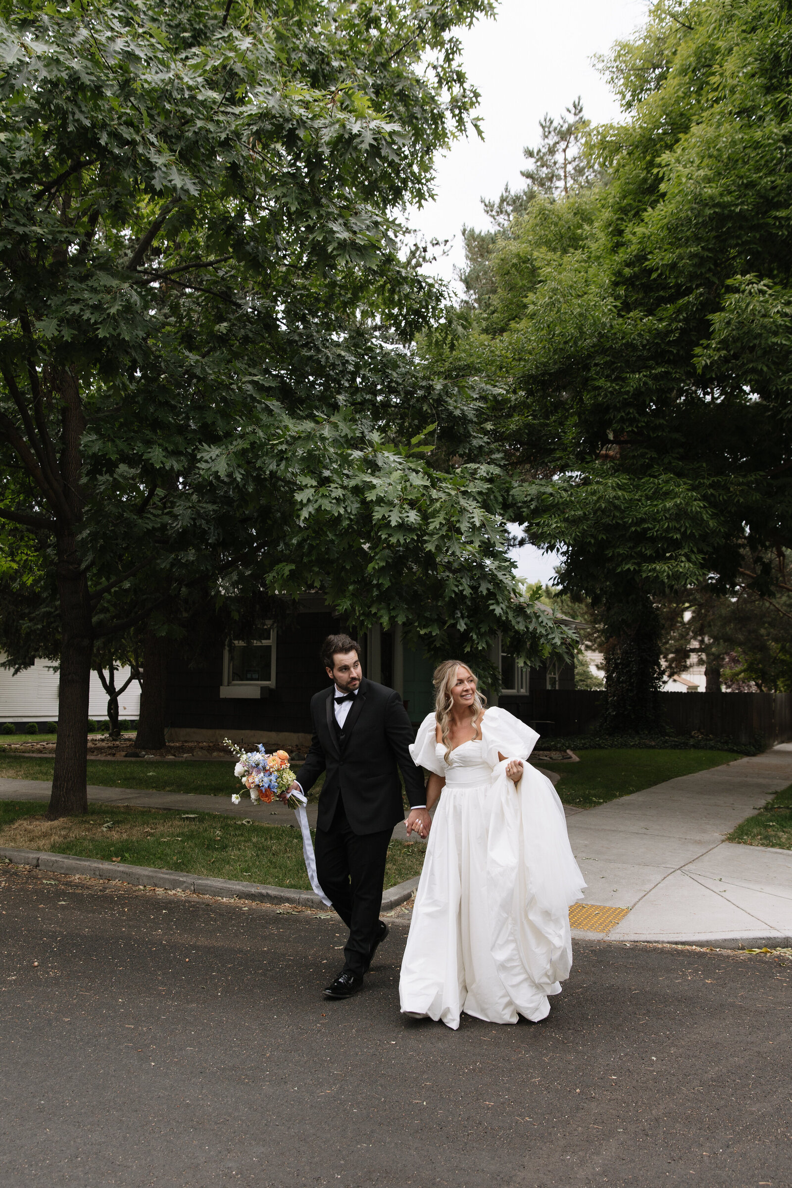 Bride and groom run across street together for modern bridal photos in Downtown Boise