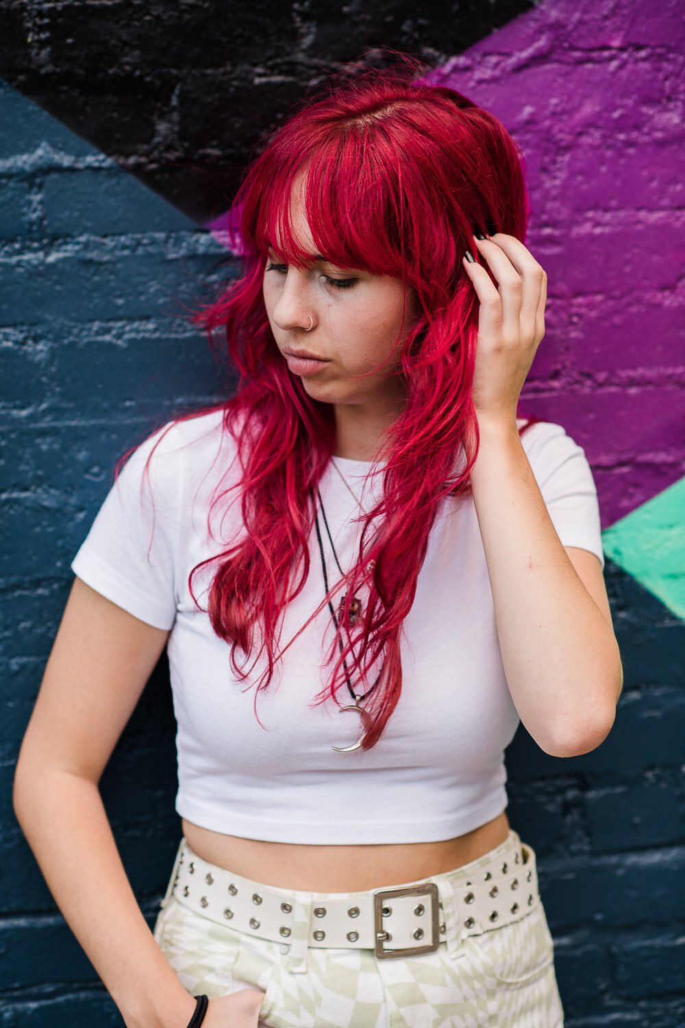 senior girl looking down in front of colorful brick wall