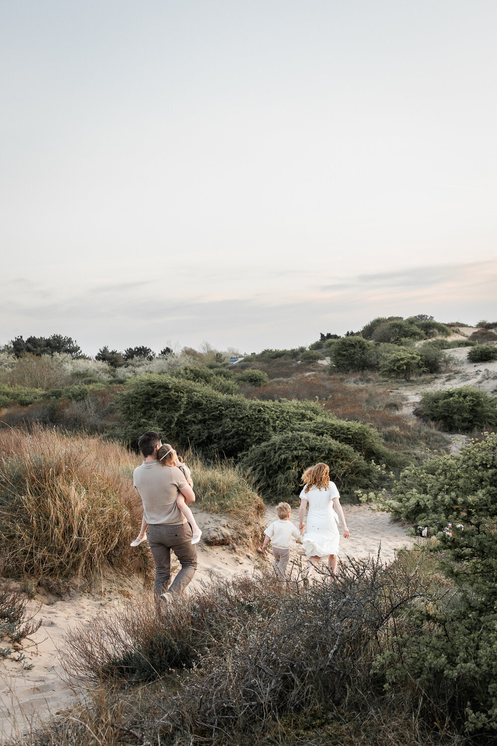 Een gezin loopt door de duinen, de kinderen moe aan het eind van een hele fijn gezinsshoot.