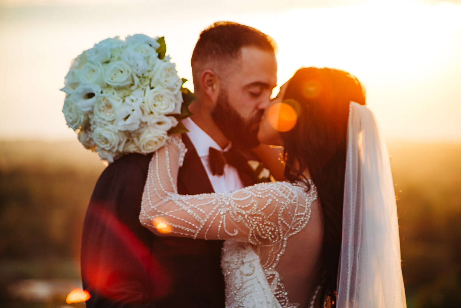 Bride and groom kissing at sunset