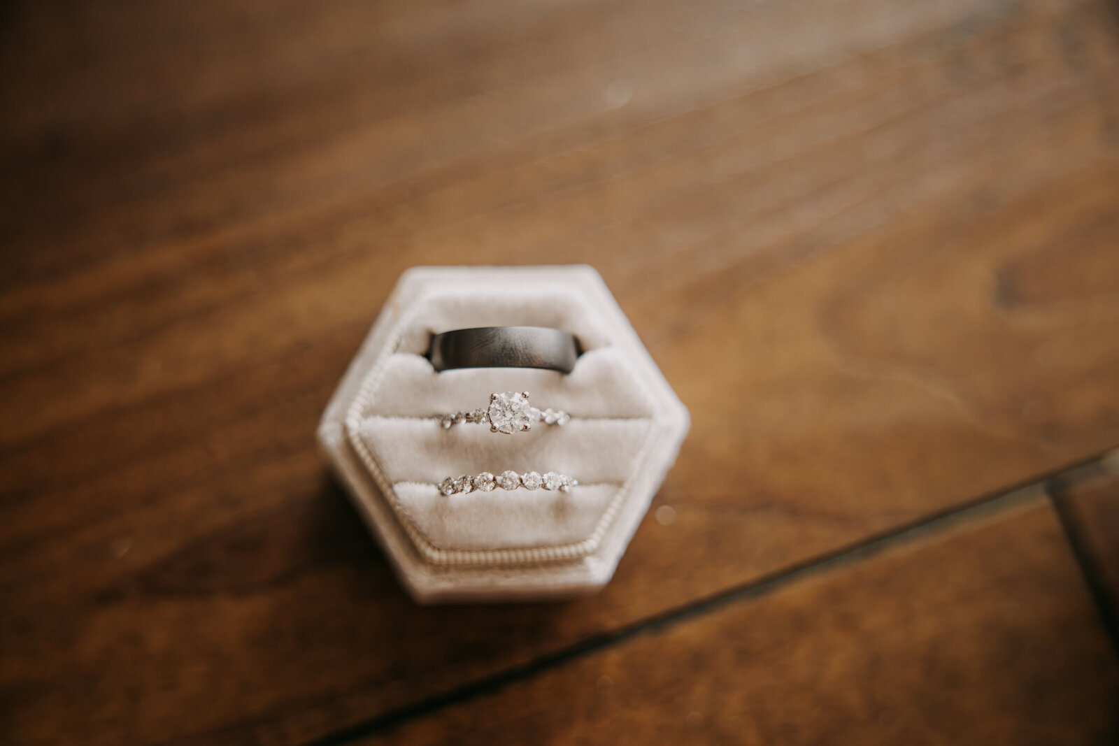 Close-up of bride and groom rings in a white velvet ring box, highlighting their elegant and timeless design.