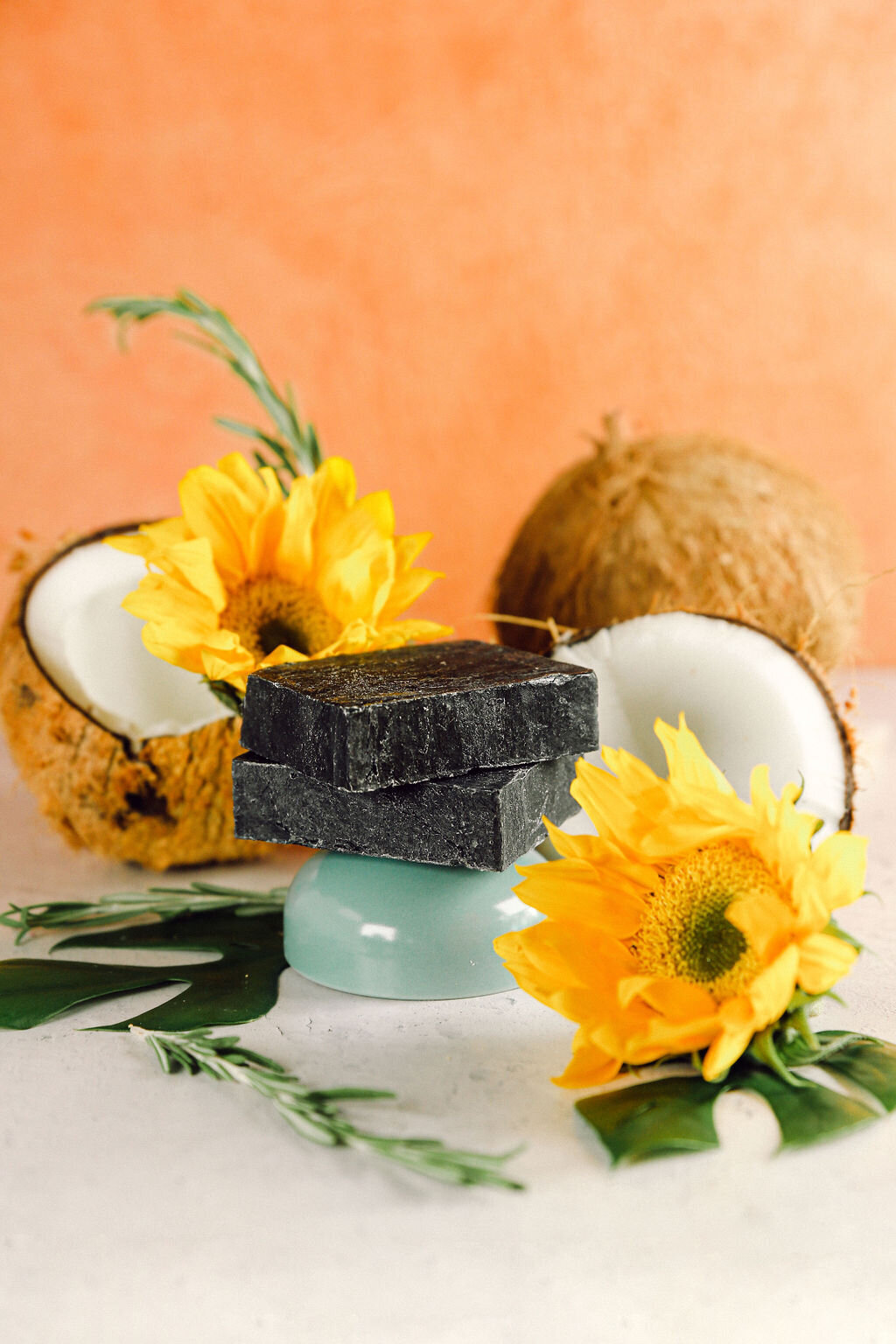 Charcoal soap product photography styled with coconuts and sunflowers for a fun, fresh, and vegan small business.
