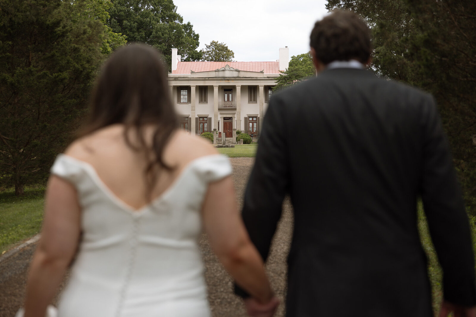 Newlyweds hold hands as they walk towards the historic Belle Meade Winery for their wedding reception.