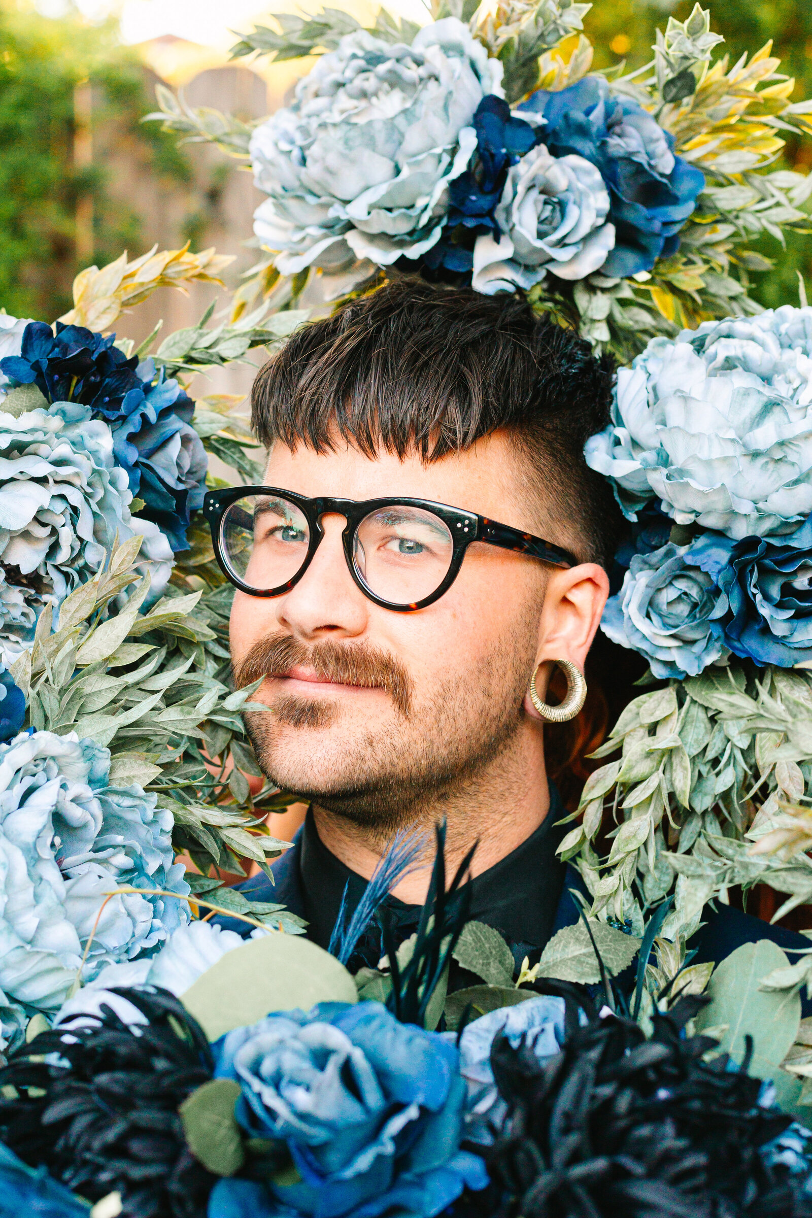 Tattooed groom with colorful wedding flowers.