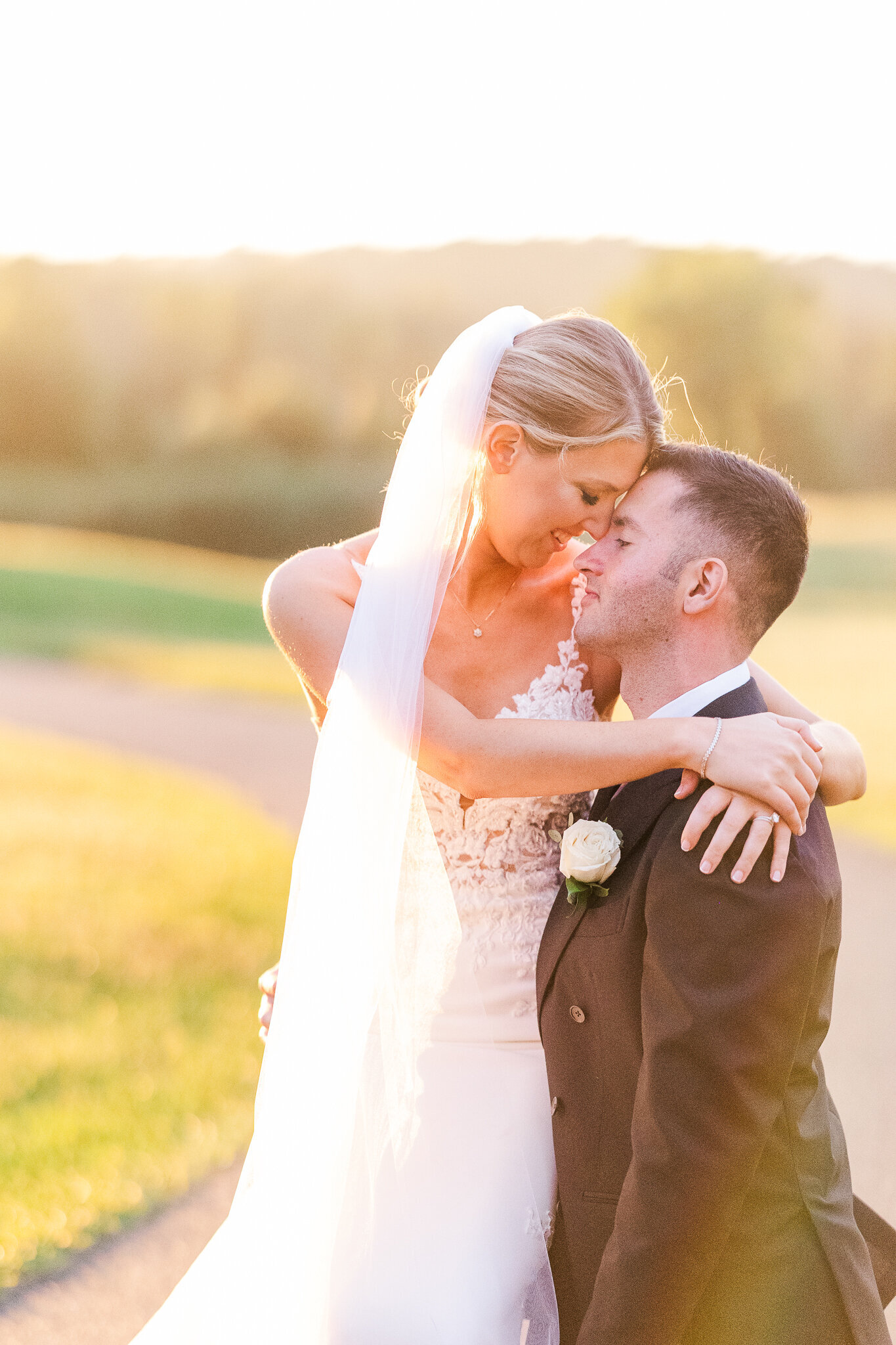 Bride sitting on groom’s knee during golden sunset at SkyView Golf Club