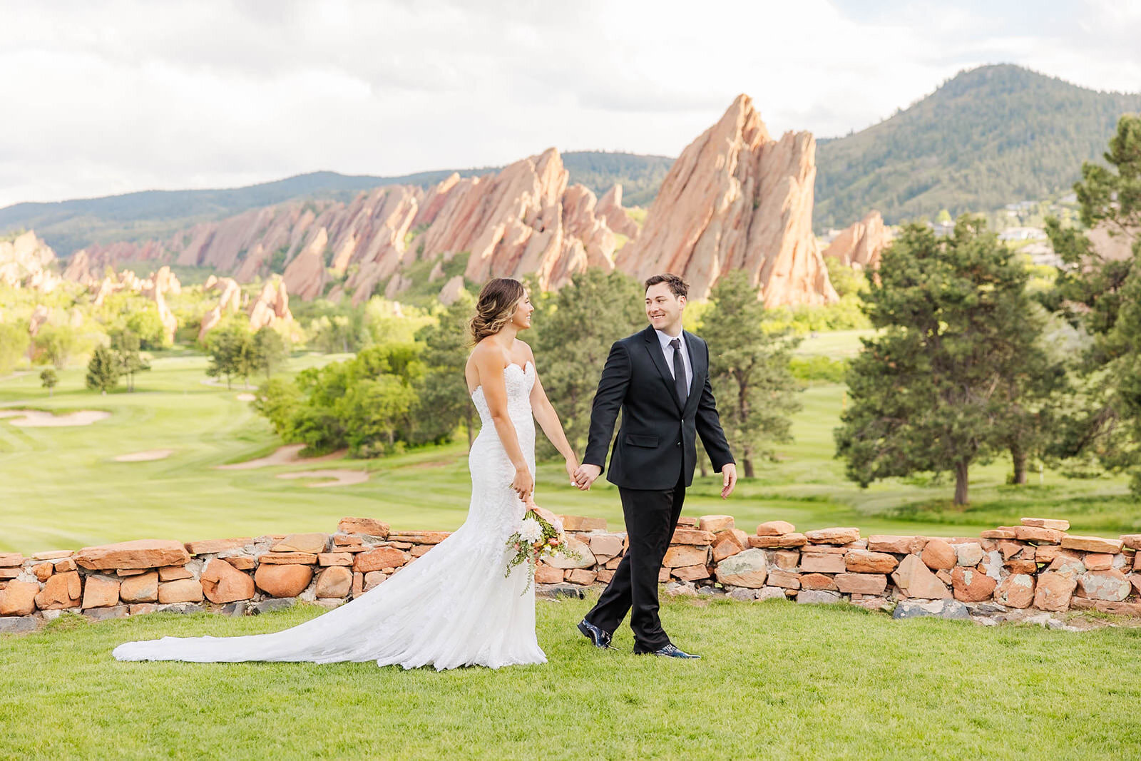 Bride and groom holding hands walking together at their wedding in Littleton, Colorado at the Arrowhead Golf Course.
