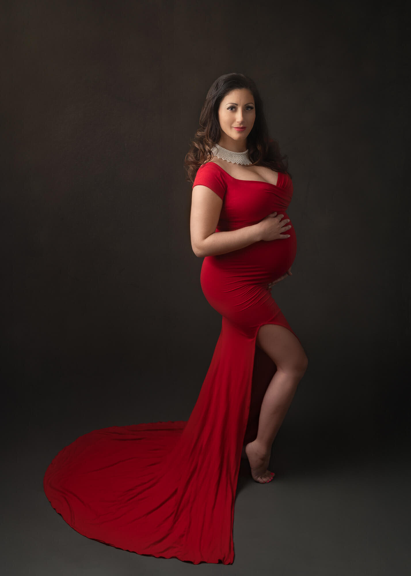 Fine-art maternity portrait of beautiful pregnant woman in red gown