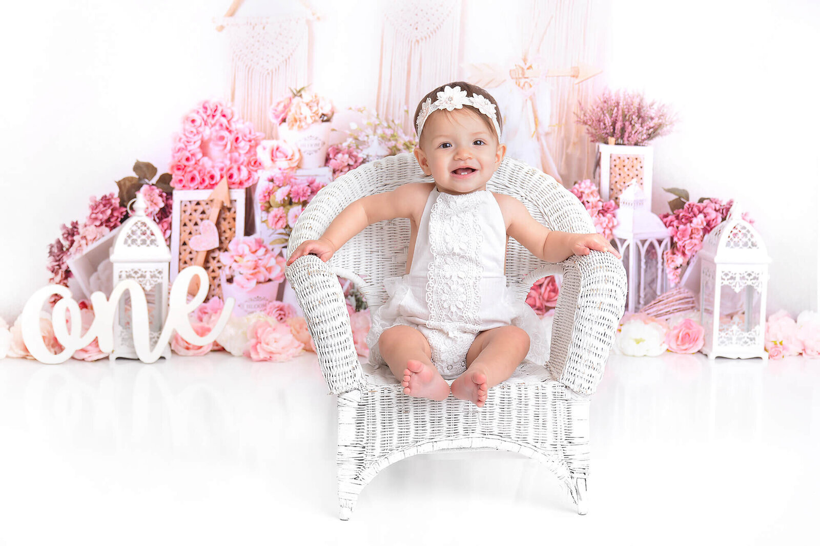 girl smiles while sitting  in a white chair at her oho themed session