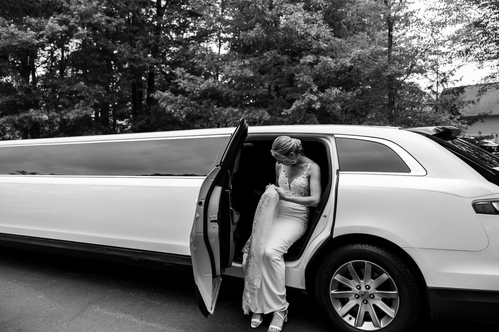 Black and white image of bride stepping into limo outside SkyView Golf Club in Sparta, New Jersey