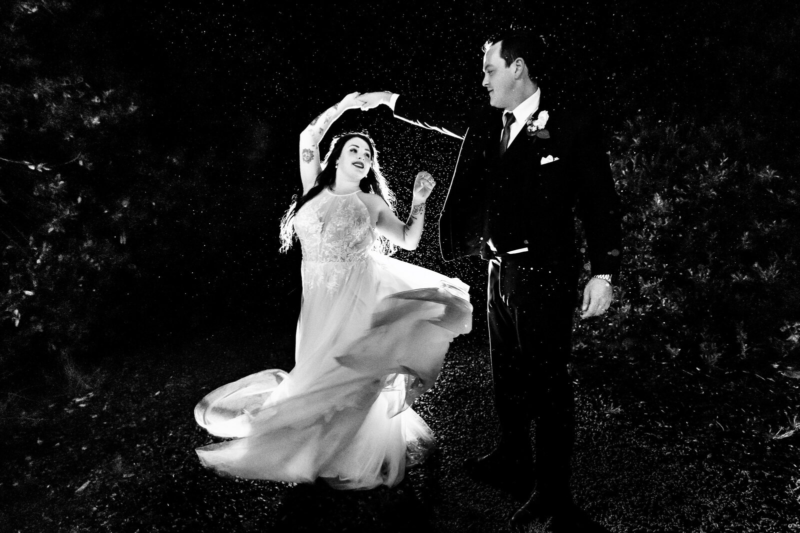 newlyweds dance in the dark in the rain in this creative wedding photo at night