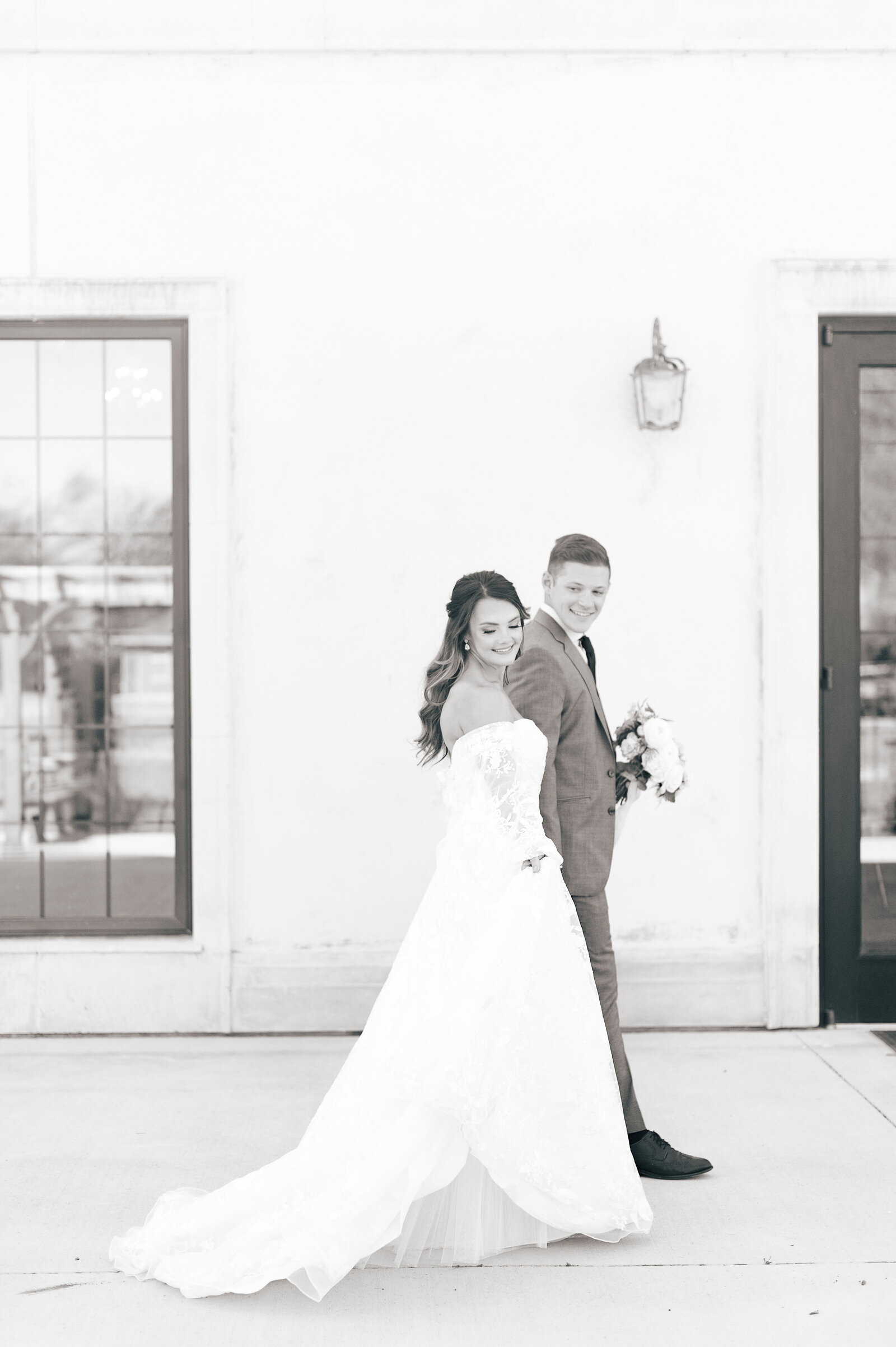 Chateau Des Fleurs Wedding bride and groom walking outside white stucco building in black and white