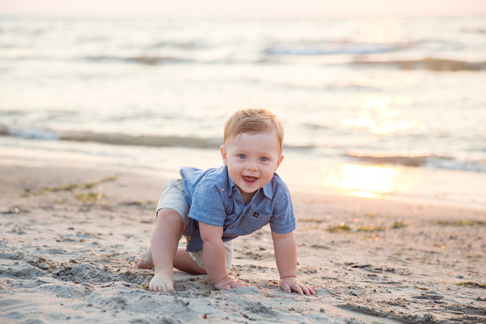 little boy crawling in the sand at the beach