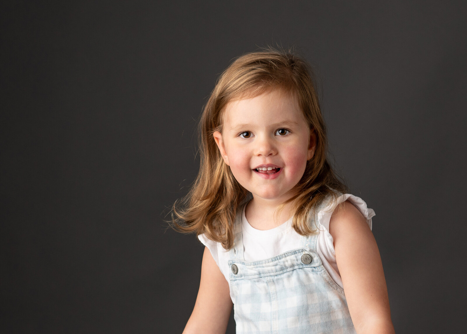 A cute young girl smiling for her school portrait session.