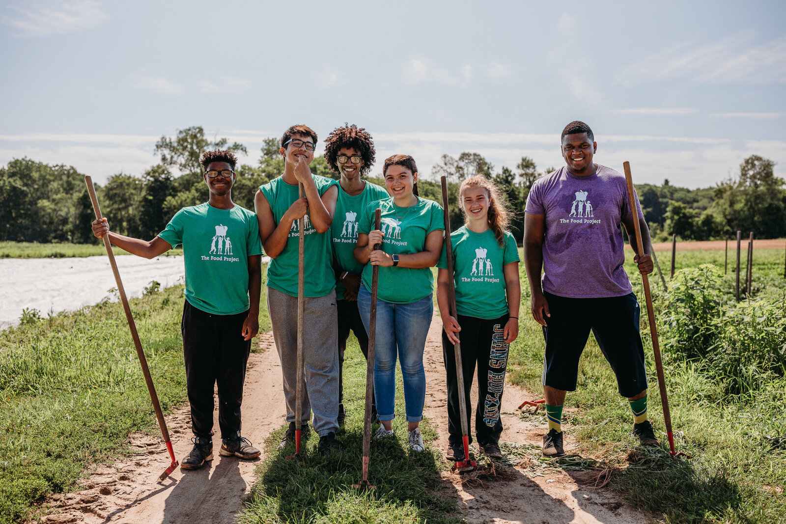 farm team holds equipment and smiles for portrait