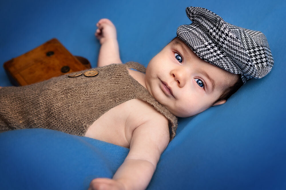 baby-blue-eyes-blue-background-paige-hat-overalls-suitcase-brown