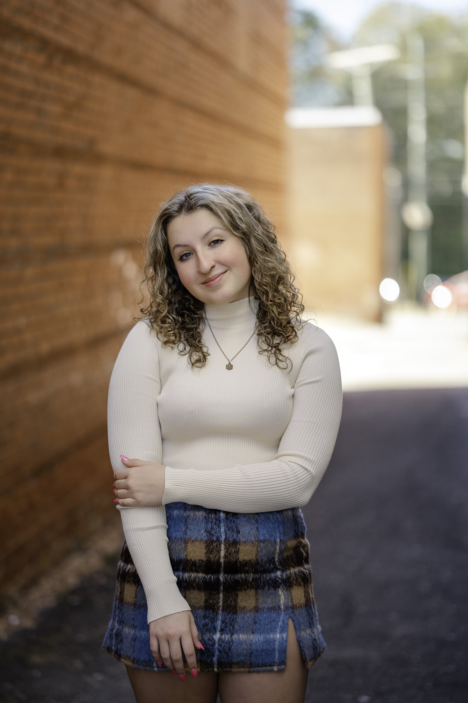 Senior girl with beautiful curly hair smiles during her senior photos