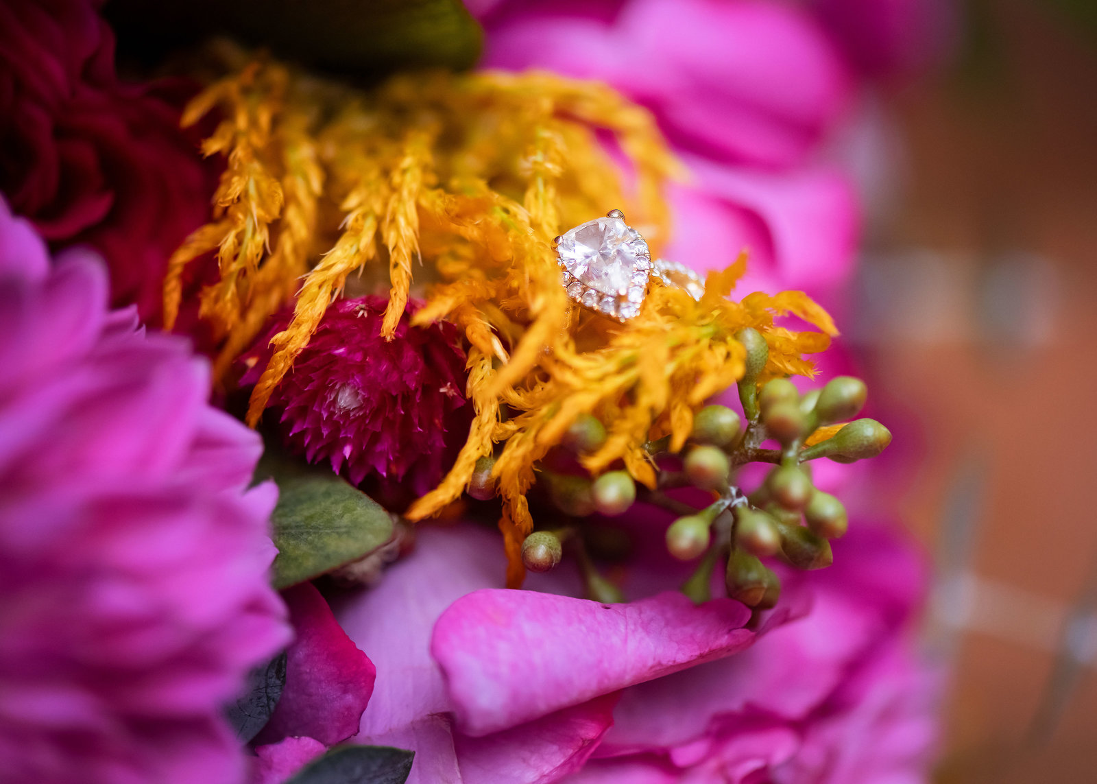 A one carat, luxury, oval cut diamond laying in the yellow and pink bridal bouquet.