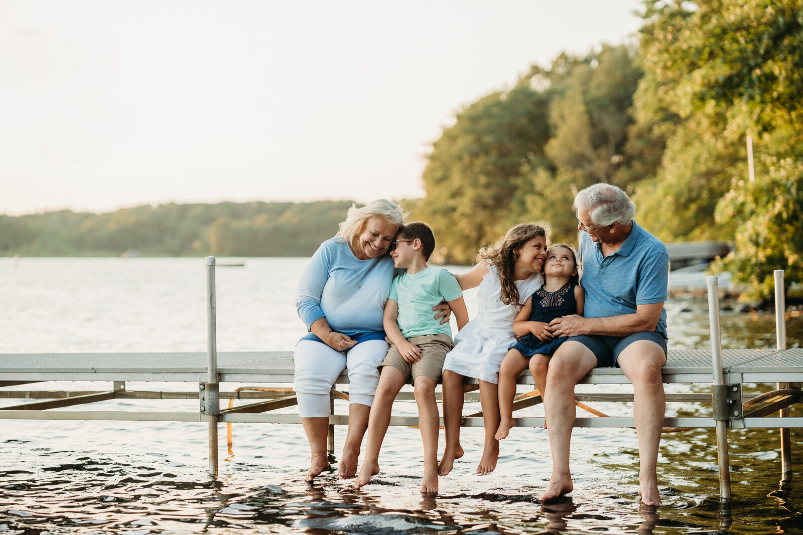 kids and grandparents sit on dock