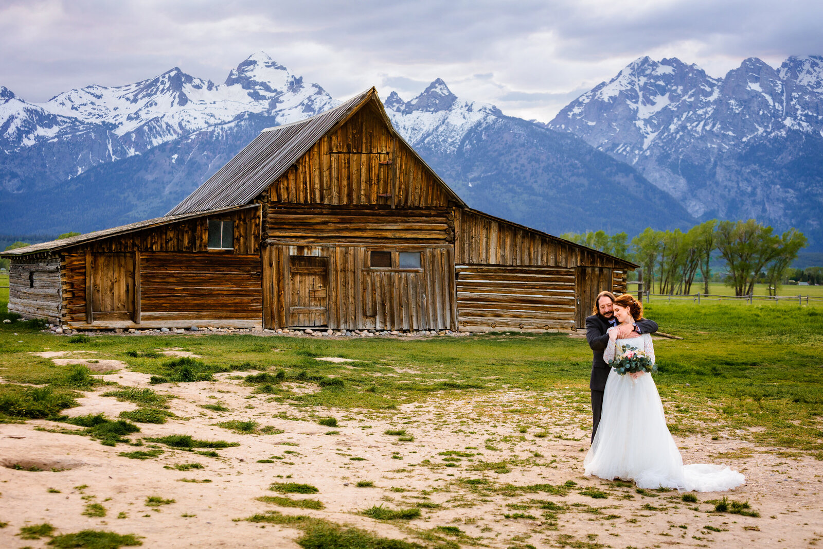 Mormon Row Jackson Hole wedding  in grand teton national park with groom hugging bride from behind.