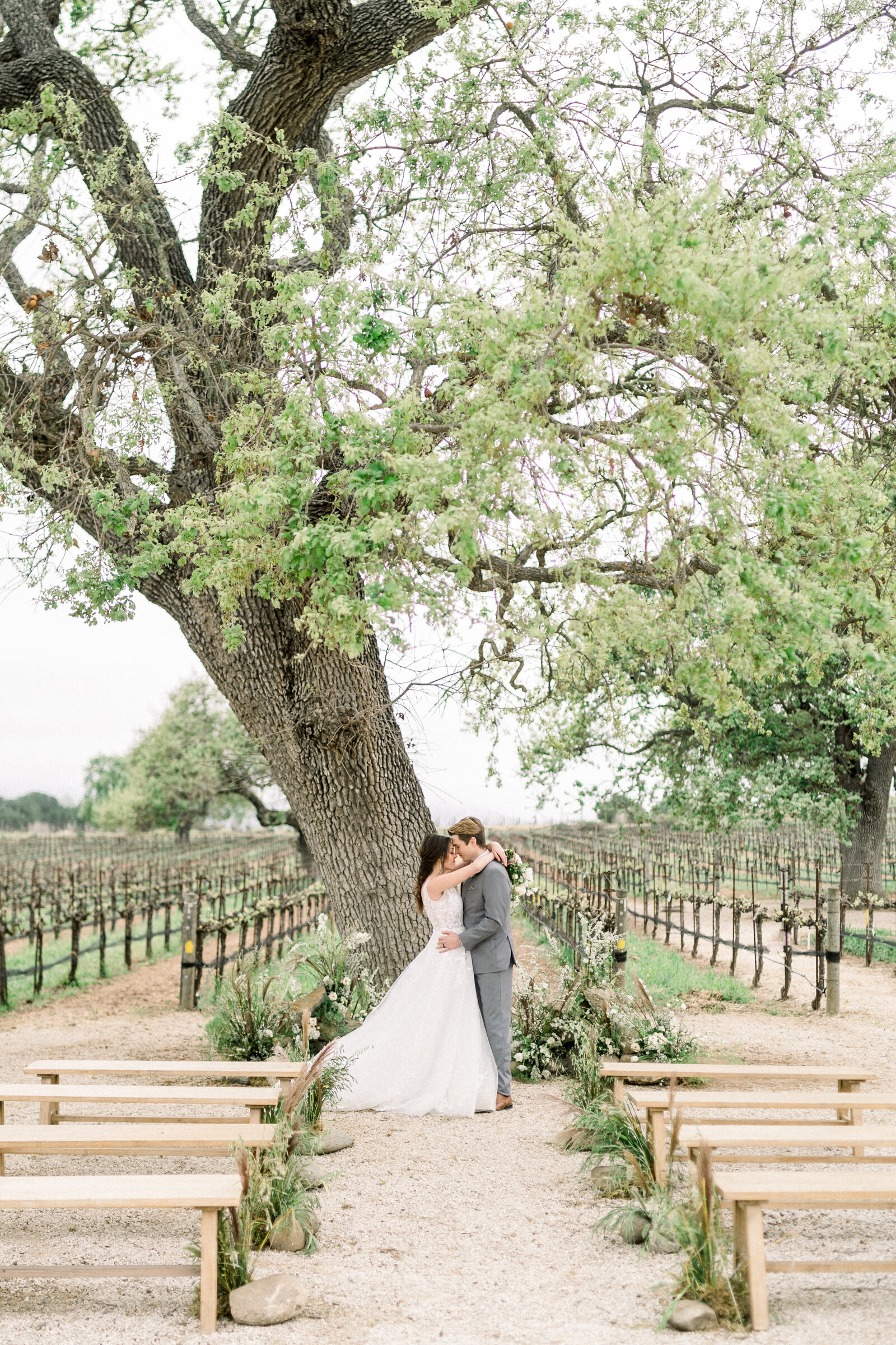 Couple at the alter under the oak tree at their Sunstone Winery wedding in Santa Ynez, CA