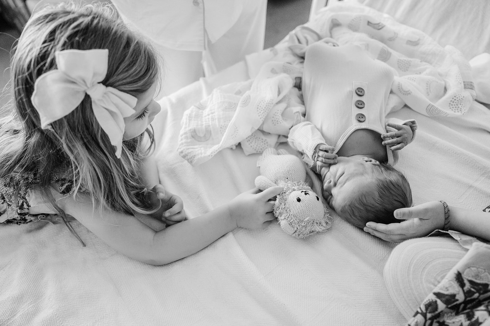 big sister gives stuffed lion to new baby brother in hospital