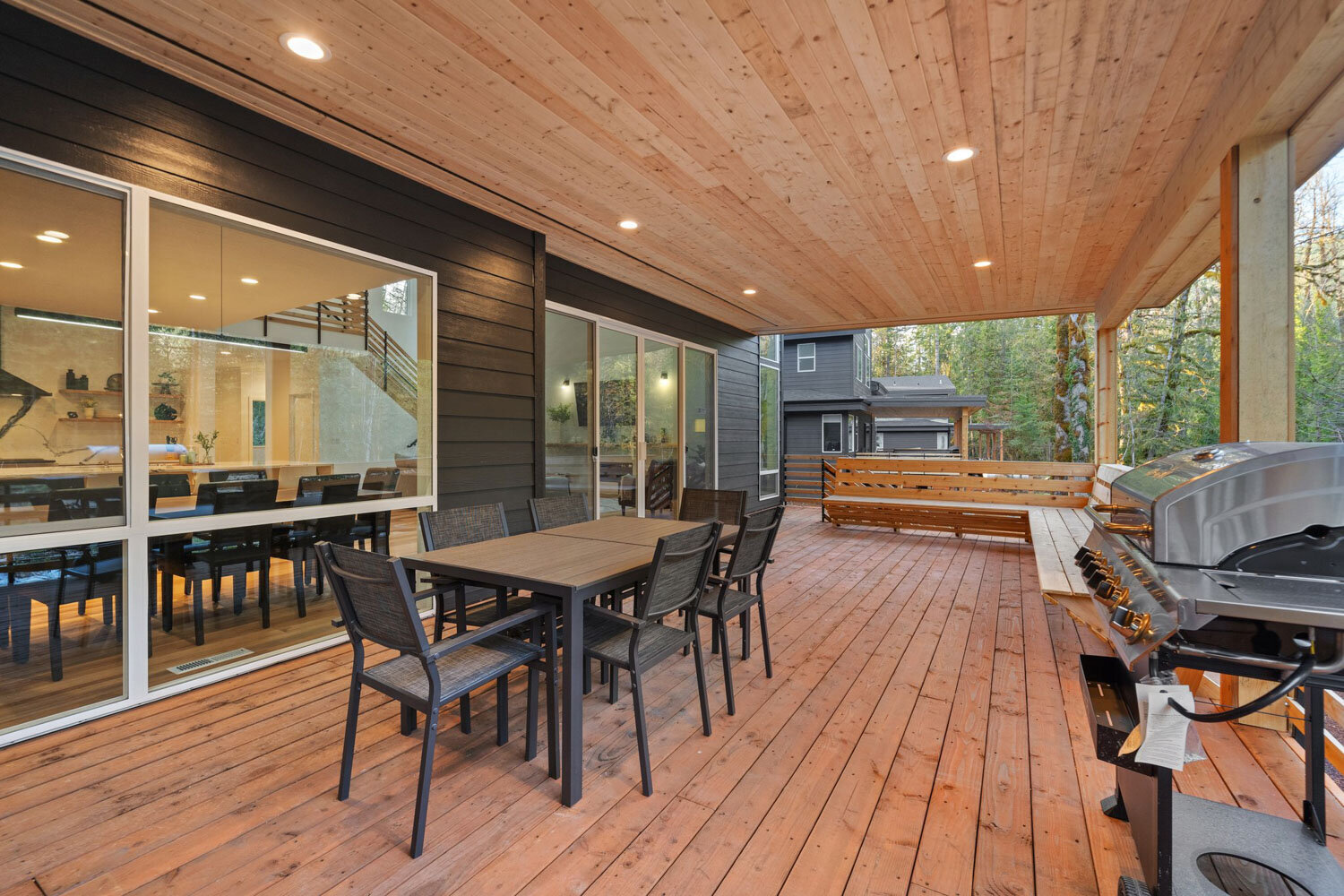 Side view of a spacious outdoor deck with wooden benches and glass doors