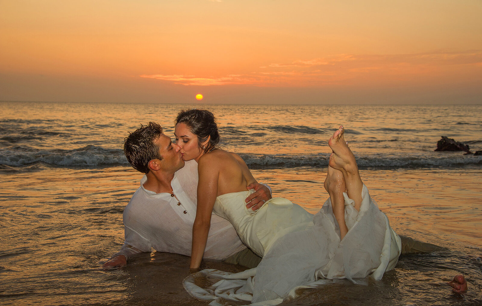Couple at sunset lying on top of each other in the water at sunset on a Oahu beach