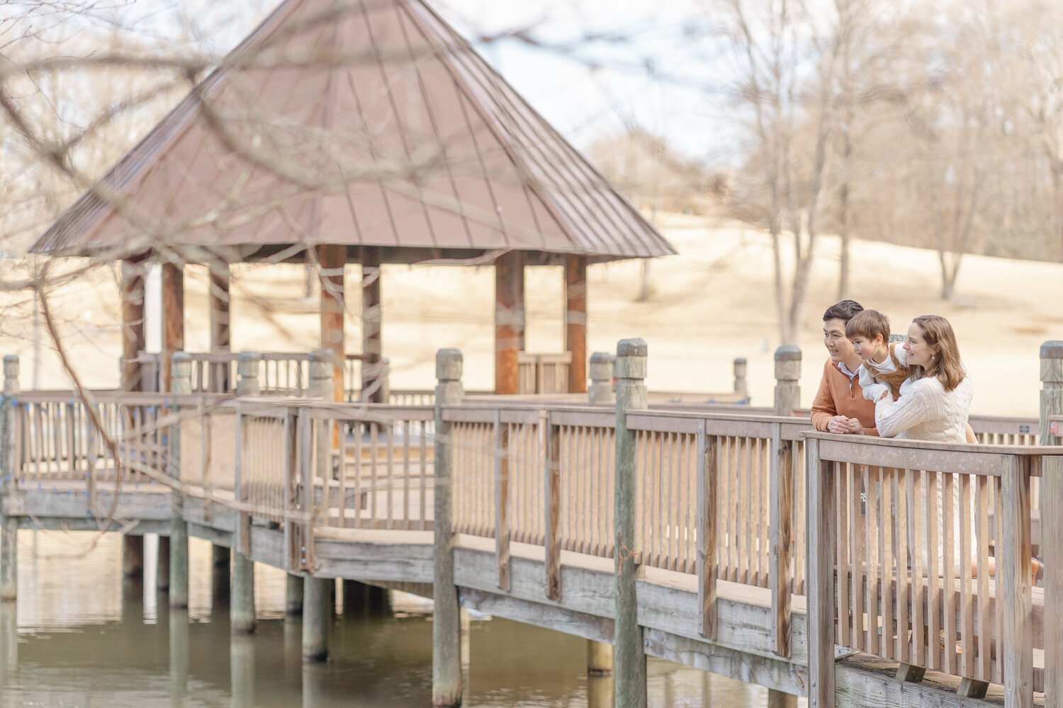 family of 3 looking over a gazebo during Fairfax County, VA maternity session