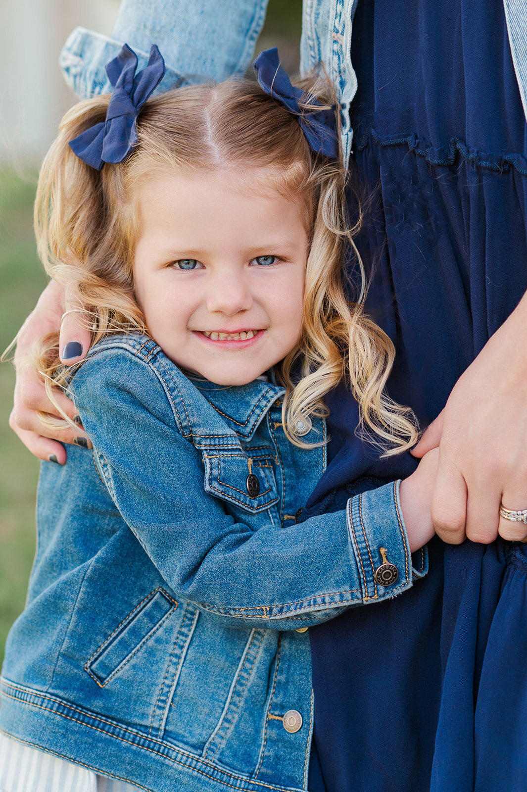 Little girl in a denim jacket, hugging her mommy's legs by Baltimore photographer