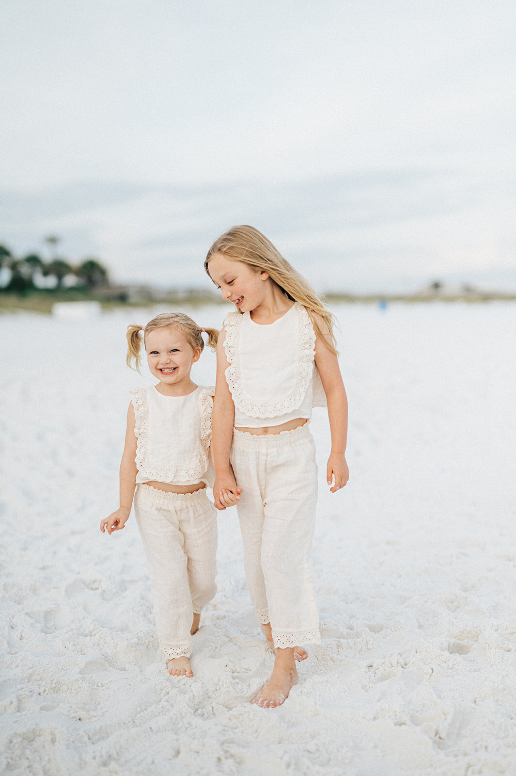 two little girls holding hands playing on the beach by Family Photographer Casey McMurray