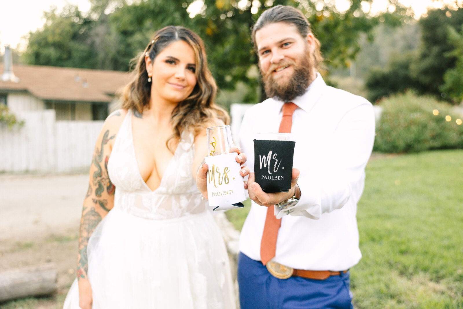 Tattoo bride and groom cheers with beer on their colorful wedding day in Santa Cruz, California.
