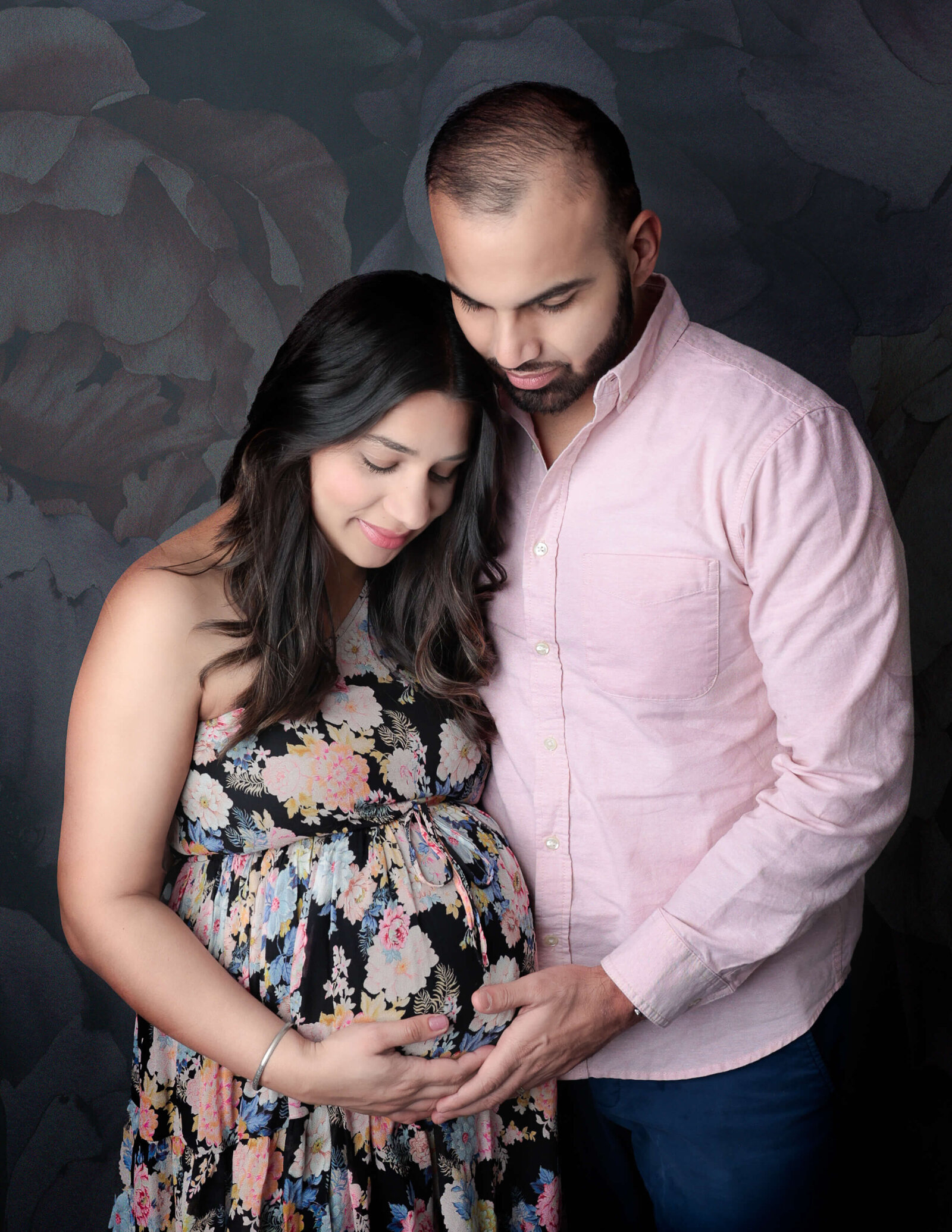 Posed couple holding moms belly in our Rochester, Ny studio.
