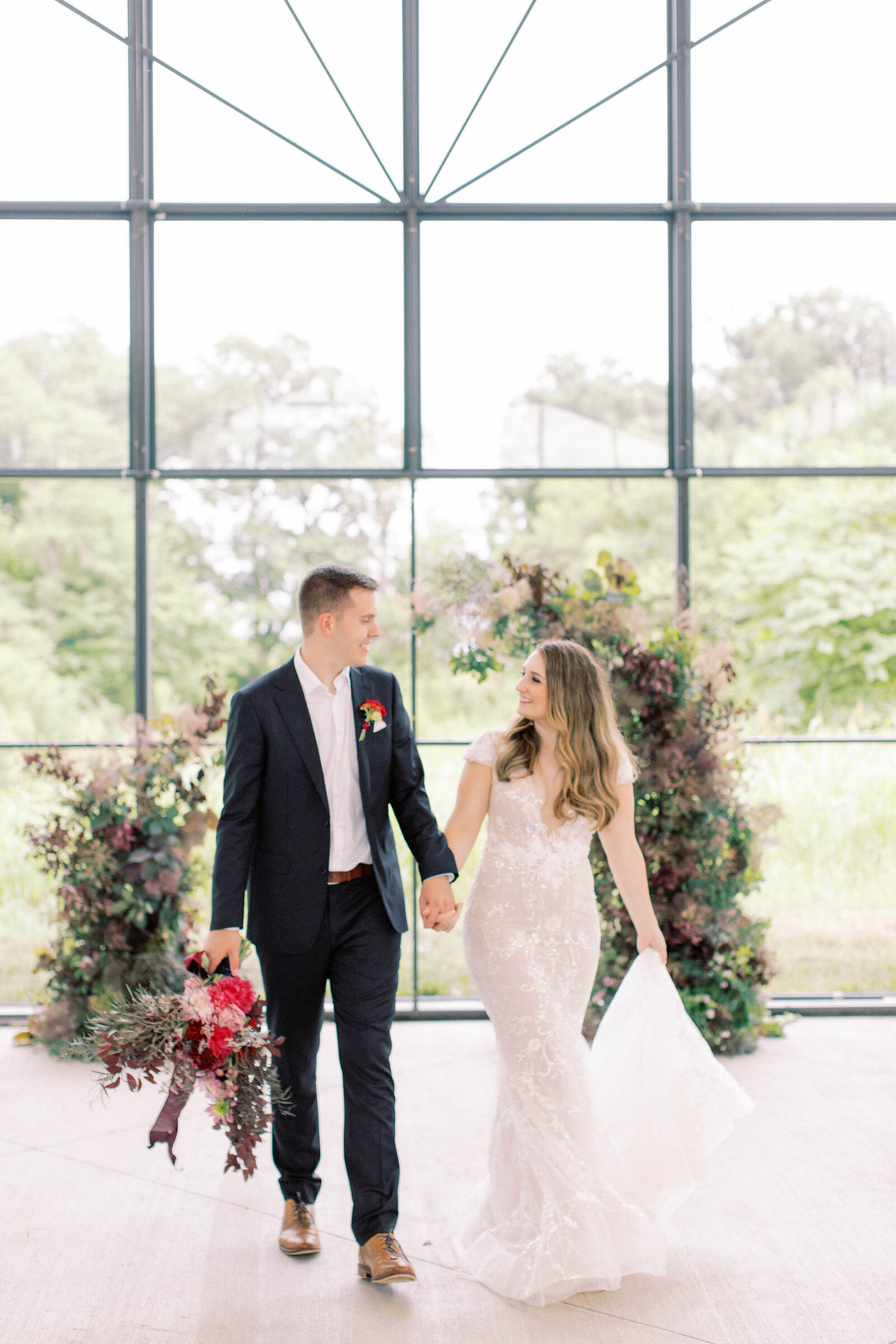 Bride and groom walk holding hands in front of floral altar at A-Vent Event Space