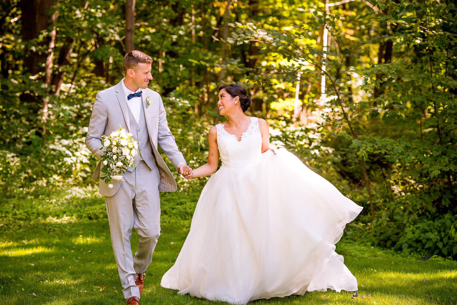 Bride and groom walking hand in hand with bridal bouquet.