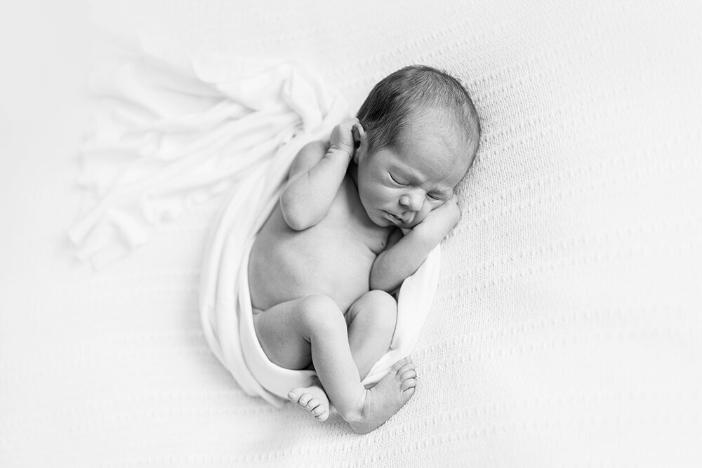 Newborn Photography, black and white image of newborn baby asleep on white background