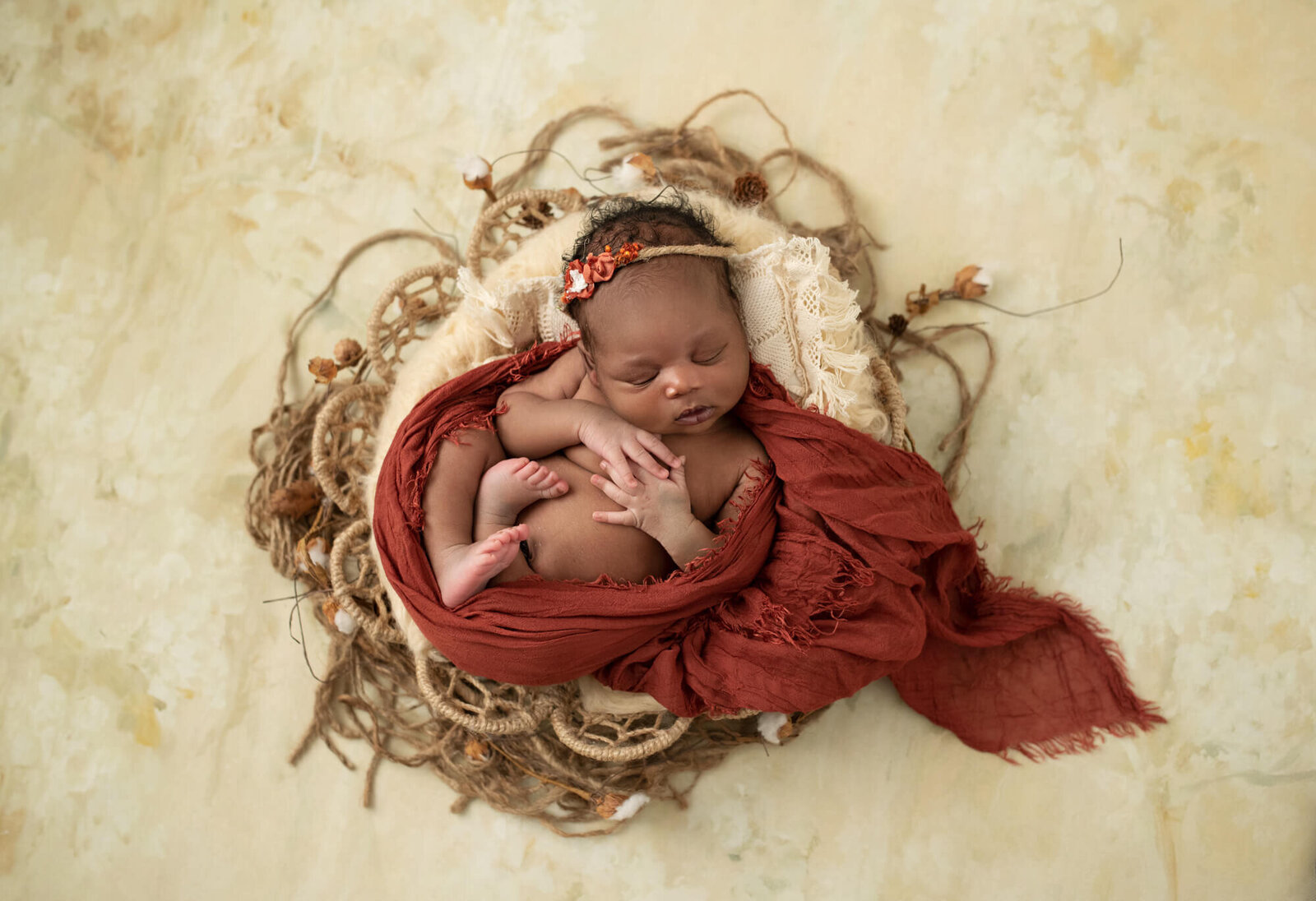 newborn girl with red wrap and cream basket