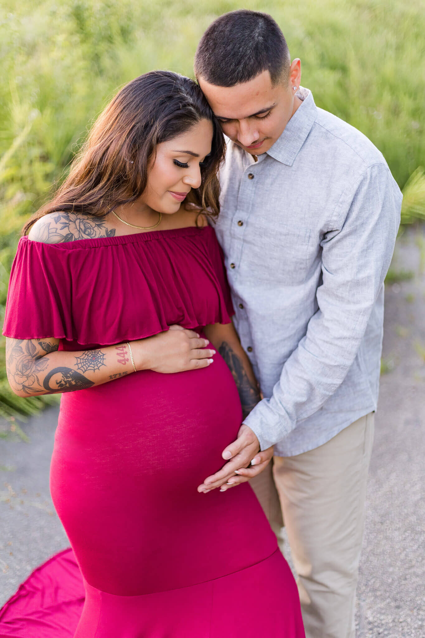 An expecting couple snuggled up together with dad holding her belly.