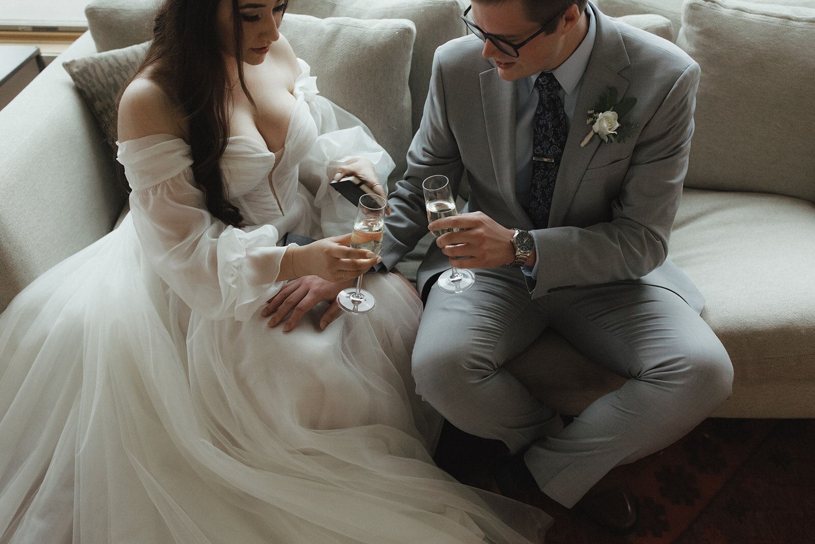 Bride and groom sitting down while tossing their wine glasses