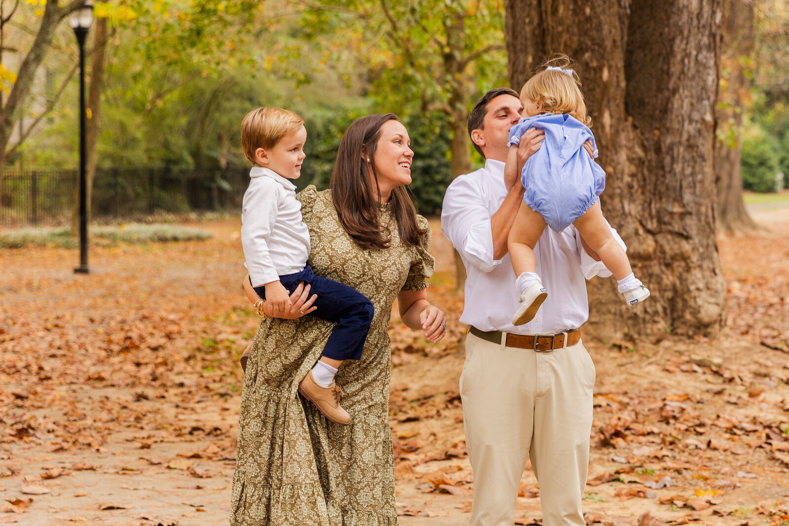 family holding toddler kids in an Atlanta park during photoshoot with Laure Photography