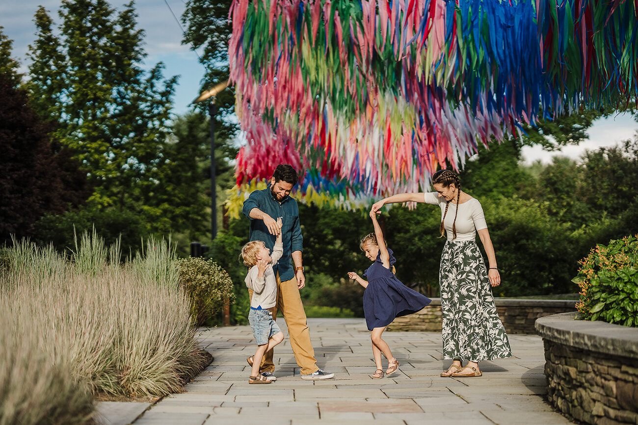 family twirls kids under rainbow art installation at boston botanical garden